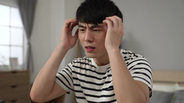 closeup shot of a frustrated asian young man working from home is holding his head in despair over an unexpected error on the computer device
