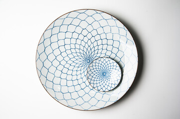 Top view of small porcelain plate with blue pattern on huge isolated on white