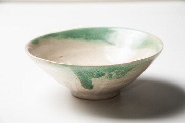 Close of vintage porcelain bowl with green pattern on white backdrop