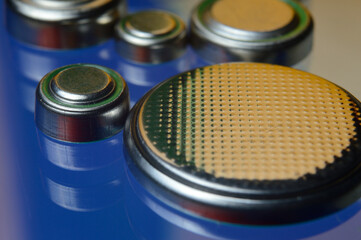 small button batteries of different sizes, highlighted in red and orange, lie against a blue background. close-up.