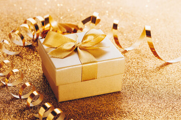 Small gift box with bow on gold glitter background
