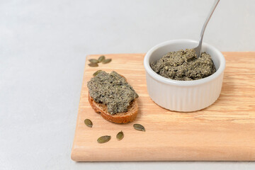 Probiotic-Cultured Vegan Cheese Paste made from pumpkin seeds spread on top of bread slice with...