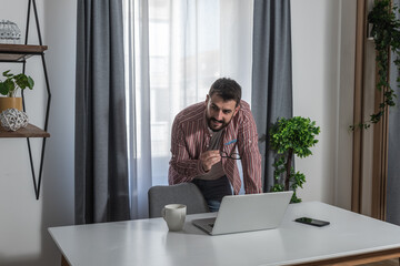 Young writer with glasses writes a new book on laptop thinking about ideas to make the book as imaginative and interesting as possible and to complete it before deadline given to him by the publisher
