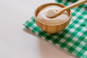 bowl of refined sugar on a green and white checkered tablecloth. 45 degree angle