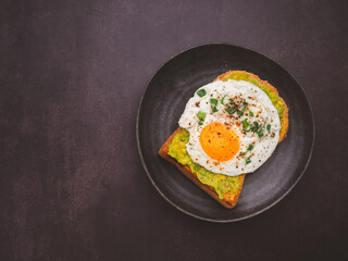 Toast with avocado and eggs served on a plate. Top view. Space for text