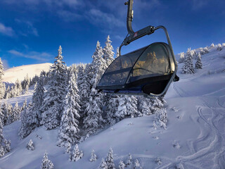 Scenic view of snowy forest with tall trees and chairlift on sunny day