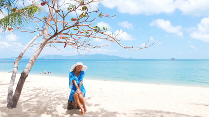 Obraz premium Young beautiful women in the blue tunic on the sunny tropical beach
