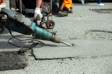 He removes the asphalt with a jackhammer. Removing the asphalt layer from the road.