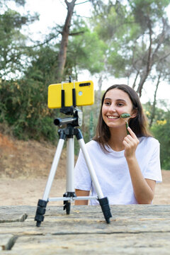Blogger massaging face with roller while recording video on smartphone