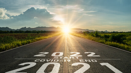 Vaccination 2021 concept.Word 2021 start covid-19 vaccine end 2022 written on the road in the...