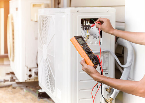 Air conditioner repairman using electricity meter to check air conditioner operation, maintenance concept	