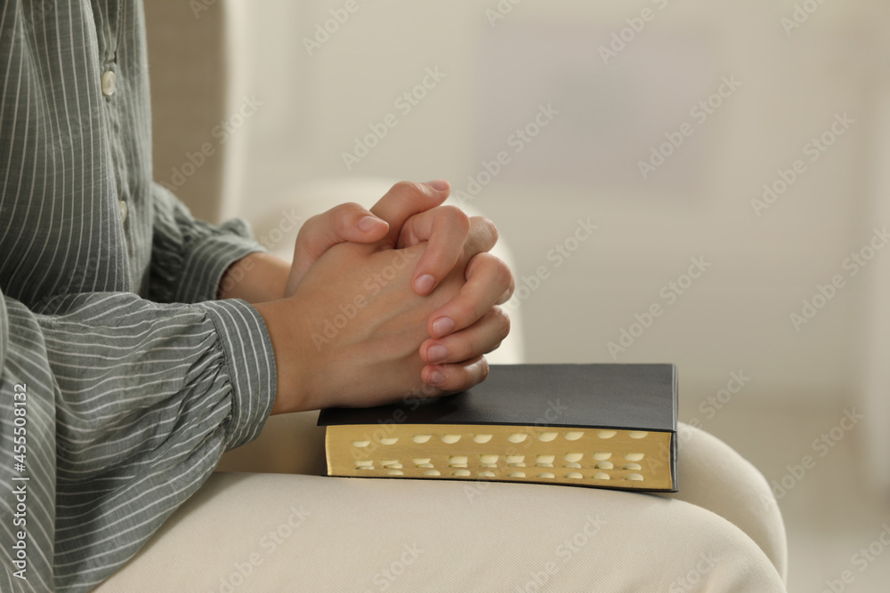 Wall mural Religious woman praying over Bible indoors, closeup