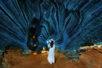 Beautiful girl in white dress walking in blue cave, Thailand.