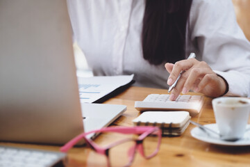 Fototapeta premium Business woman using calculator to review balance sheet annual using document and laptop computer to calculating budget. audit and Check integrity before investment concept.