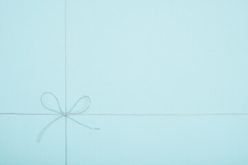 Silver string tied in a bow on light blue background