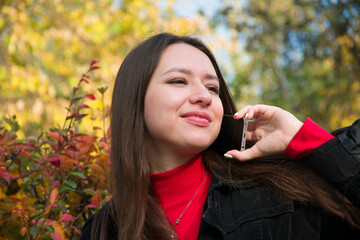Fototapeta premium Pensive woman talking on phone in autumn park