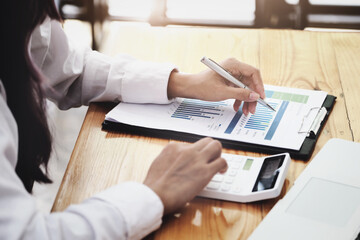 A businesswoman using pen point to chart document is researching earnings affected by the coronavirus pandemic to adjust her market strategy.