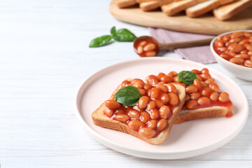 Toasts with delicious canned beans on white wooden table, space for text