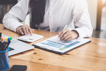 A businesswoman using pen point to chart document is researching earnings affected by the coronavirus pandemic to adjust her market strategy.