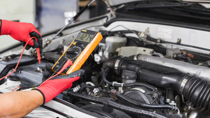 A technician is checking the car battery for availability.	