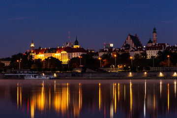 Fototapeta na wymiar Illuminated Warsaw Old Town landscape with the Royal Castle, Cathedral and medieval buildings, night view with reflections in calm Vistula river, Poland.