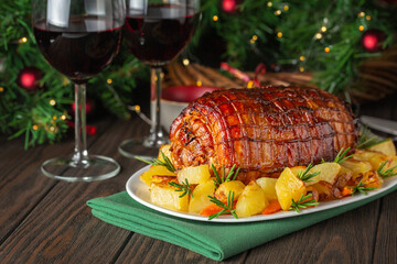 Baked veal roulade with potato and rosemary. Red wine glasses. Christmas holiday dinner on a dark...