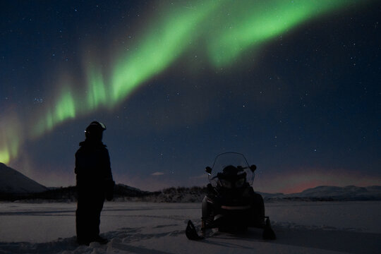 snowmobile and man with aurora borealis