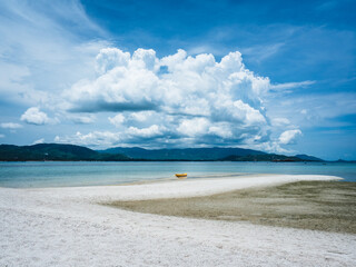 Obraz premium Scenic peaceful white sandbank with yellow kayak and crystal clear sea water of tropical island with fluffy cloud blue sky background. Koh Mat Sum Island, Near Koh Samui, Thailand.