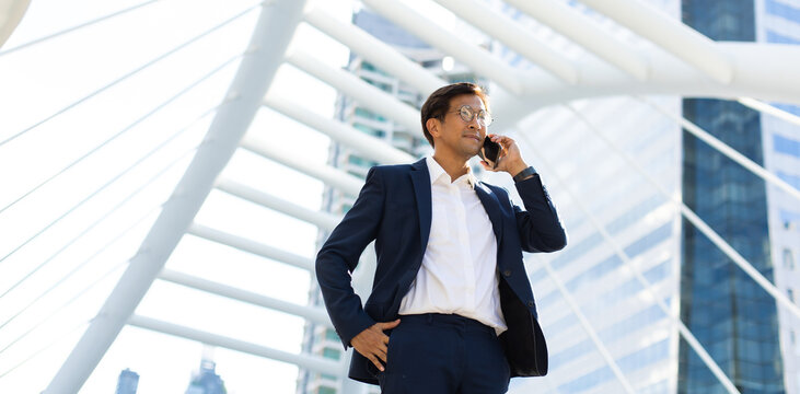 Asian Businessman Using Mobile Phone App Texting Outside The Office Building