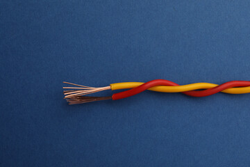 Obraz na płótnie Canvas Two twisted electrical wires on blue background, closeup