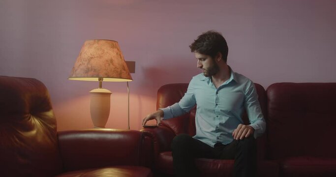 Ragazzo con camicia azzurra usa il computer portatile sulle gambe seduto sul divano