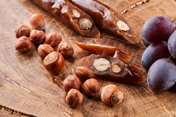 Churchkhela, national Georgian dessert made from grape juice and hazelnuts, composition on a wooden table