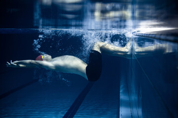 One male swimmer practicing and training at pool, indoors. Underwater view of swimming movements details. Healthy lifestyle, power, energy, sports movement concept.