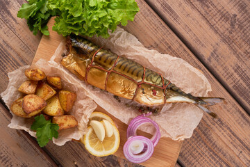 Composition smoked mackerel fish with garnish potatoes lemon greens onions served on wooden board plate top view