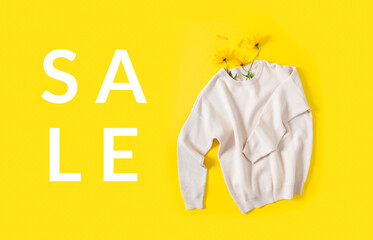 Autumn shopping, discount and sale banner concept. Knitted sweater and autumn flowers on a bright yellow background. Flat lay, copy space. Fall promotion, fashion web line