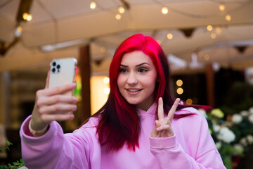 Beautiful red-haired influencer blogger girl in cafe talking making video call using smartphone with her subscribers in social networks