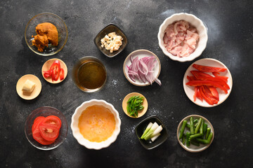 Many thai ingredients for dish gai pad pongali with chicken, eggs, spicy, yellow thai curry paste,tomato, rice in black bowl made in wok. Traditional local Thai Food Stir Fried. View from above.