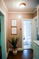 a tan colored hallway with a shiplap paneled ceiling and artwork on the walls.
