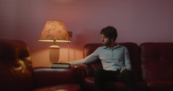 Giovane ragazzo seduto sul divano legge un libro la sera