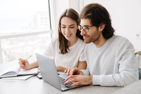 Young multiracial couple smiling while working with laptop together