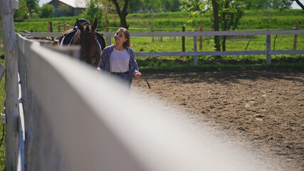 a young girl sets a horse's unbuttoned shirt by the fence. High-quality photo