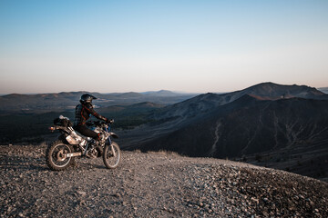 Motorcyclist on a mountain overlooking a natural landscape with mountain and forest