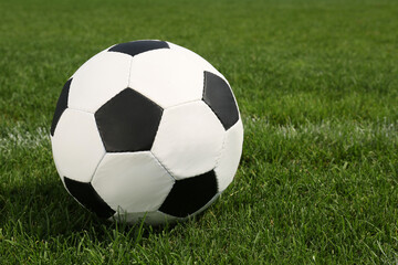 Fototapeta na wymiar Football ball on green field grass outdoors. Space for text