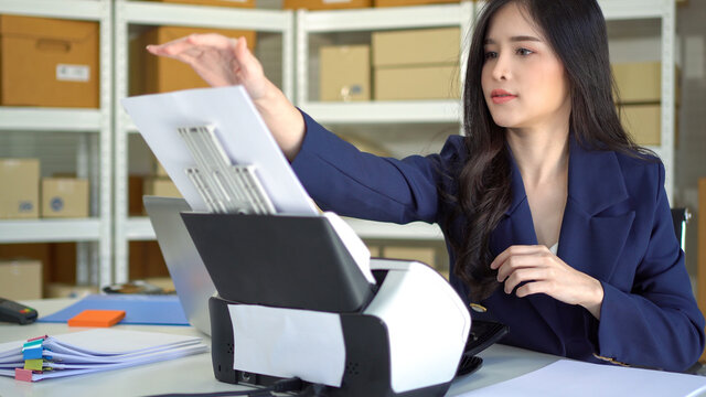 Asian women are using document scanners to transfer data to the computer.