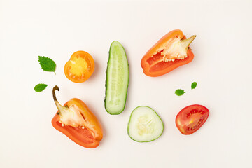 Assorted chopped vegetables on white background. Cucumber, tomato and pepper slices on a gray background