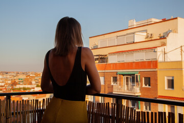 Mujer disfrutando de su terraza mirando a través de ella con edificios al fondo. Madrid desde el...