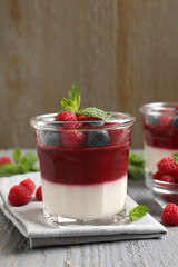 Delicious panna cotta with berries on grey wooden table