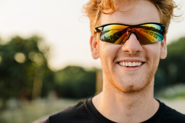 Young sportsman in sunglasses smiling while working out