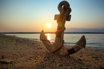Wooden anchor on shore near river at sunset © New Africa