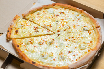 Four cheese pizza in cardboard box. Delicious Italian fast food delivered for dinner.